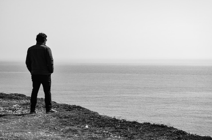 Foto vista trasera de un hombre mirando la vista del mar contra el cielo