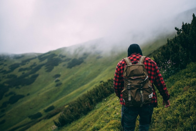 Vista trasera de un hombre con mochila caminando por la montaña