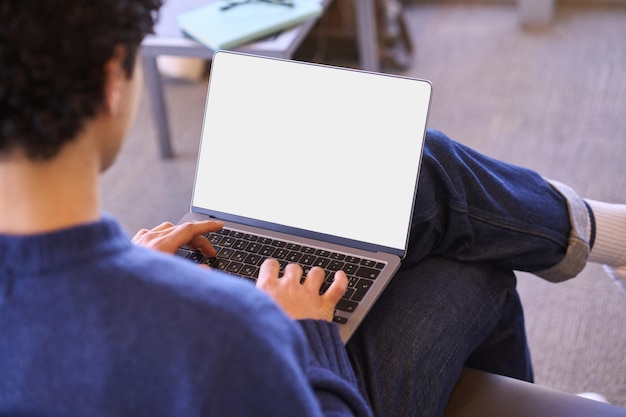 Vista trasera del hombre de negocios o estudiante que usa una computadora portátil con una pantalla digital blanca vacía con espacio publicitario gratuito