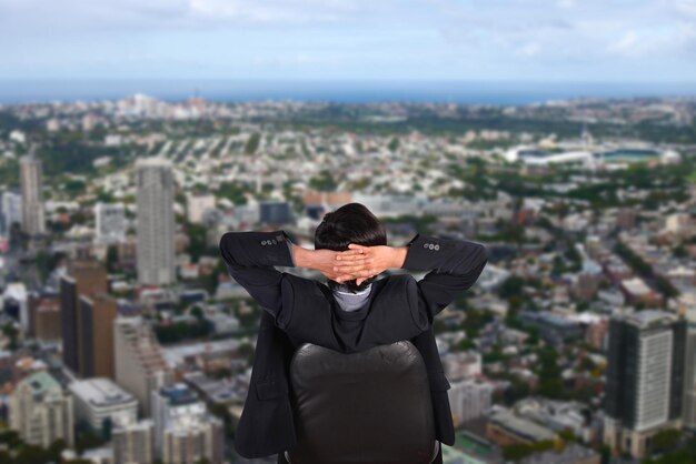 Foto vista trasera de un hombre de negocios sentado contra el paisaje urbano