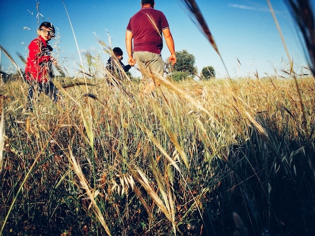 Vista trasera de un hombre con niños en un campo de hierba