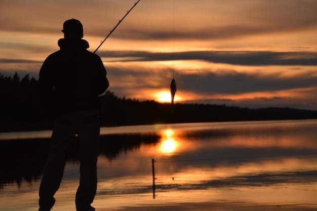 Vista trasera de un hombre pescando al atardecer