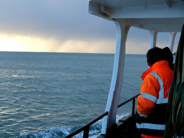 Foto vista trasera de un hombre de pie en un barco que navega en el mar