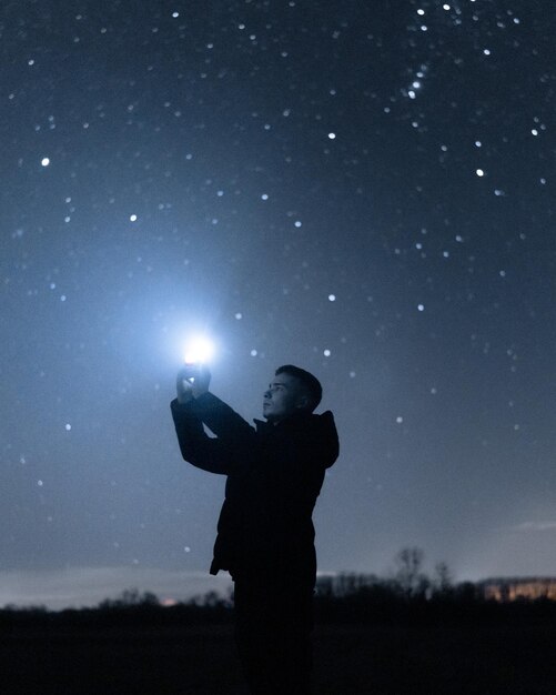 Foto vista trasera de un hombre de pie en el campo por la noche