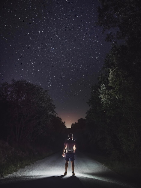 Foto vista trasera de un hombre de pie en la carretera contra el cielo por la noche