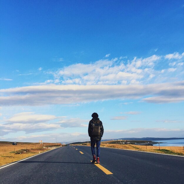 Foto vista trasera de un hombre de pie en la carretera