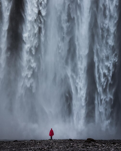 Vista trasera de un hombre de pie contra una cascada