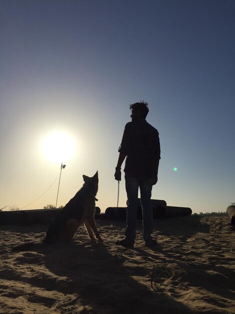 Vista trasera de un hombre de pie contra el cielo durante la puesta de sol