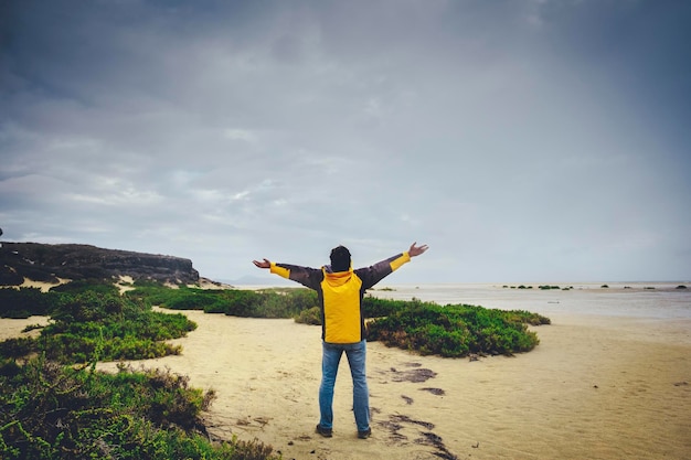 Vista trasera del hombre de pie y extendiendo los brazos contra un maravilloso paisaje salvaje en la playa. Explora y aventúrate a la gente del estilo de vida. Viaje masculino disfrutando de la naturaleza.