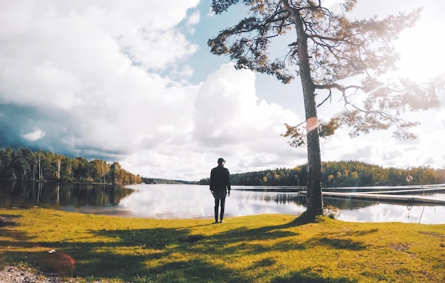 Foto vista trasera de un hombre de pie junto al lago contra un cielo nublado