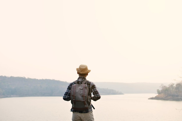 Vista trasera del hombre de pie junto al lago contra el cielo