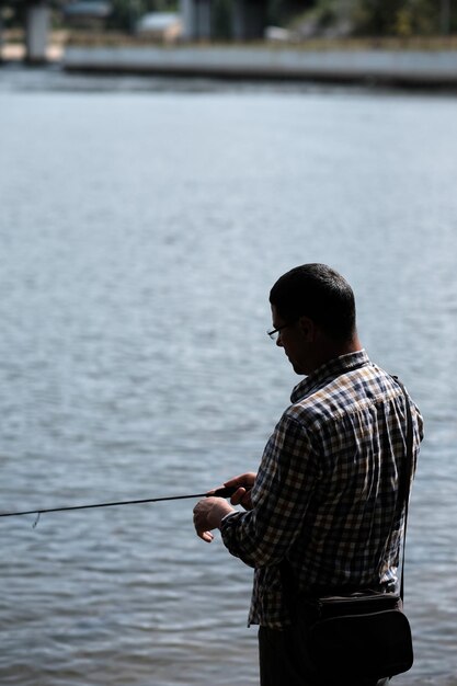 Foto vista trasera de un hombre de pie junto al lago y pescando