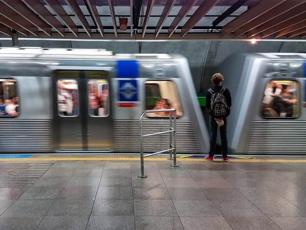 Foto vista trasera de un hombre de pie junto al tren en la estación de tren