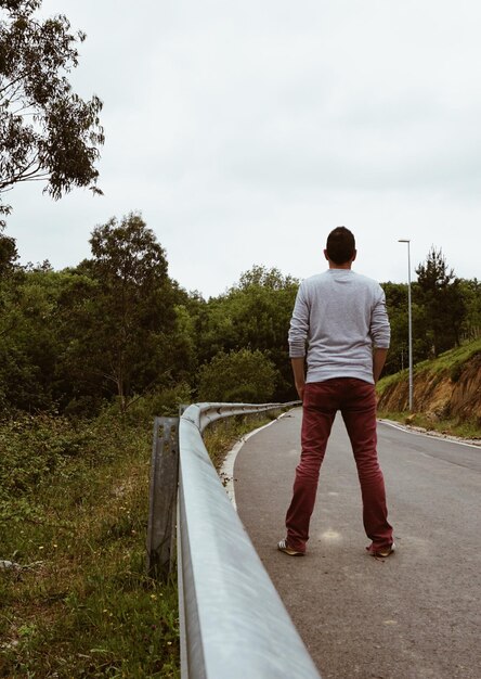 Foto vista trasera de un hombre de pie junto a la carretera contra el cielo