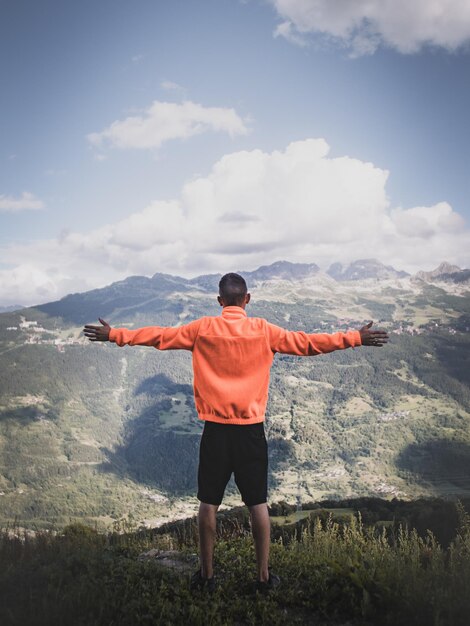 Vista trasera de un hombre de pie en la montaña contra el cielo