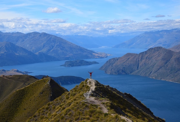 Vista trasera de un hombre de pie en la montaña contra el cielo