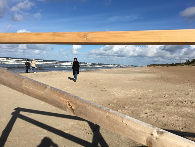 Vista trasera de un hombre en la playa contra el cielo