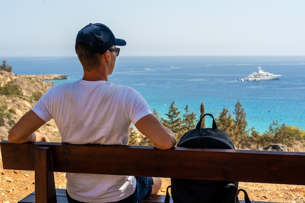 Vista trasera del hombre relajarse en un banco sentado cerca del mar Concepto Wanderlust