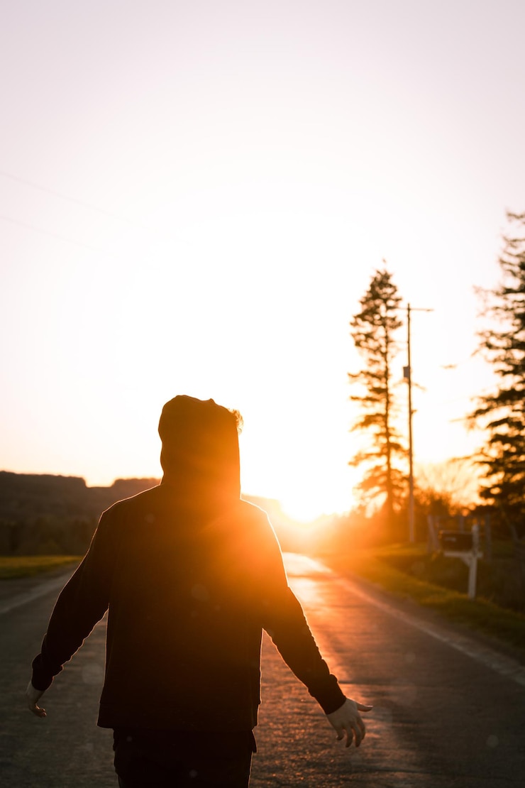 Foto vista trasera de un hombre en silueta de pie en la carretera contra el cielo durante la puesta de sol