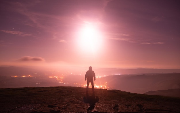 Vista trasera de un hombre en silueta de pie en la montaña contra el cielo durante la puesta de sol