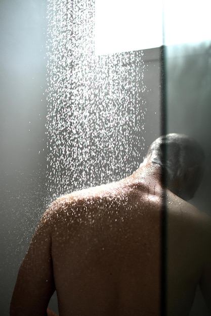 Vista trasera de un hombre tomando una ducha en el baño