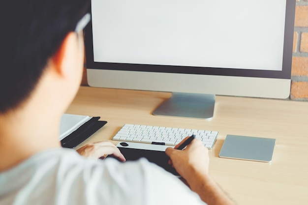Vista trasera de un hombre usando una computadora portátil en la mesa