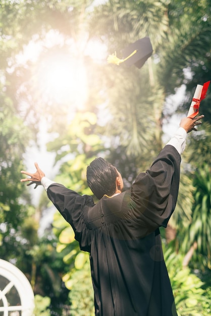 Vista trasera de un hombre con un vestido de graduación contra los árboles