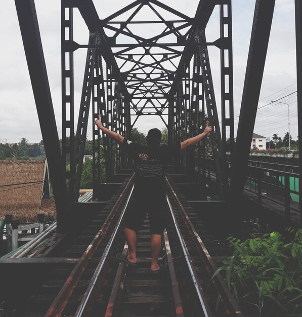 Foto vista trasera de un hombre en las vías del ferrocarril contra el cielo