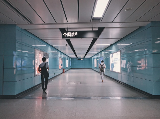 Vista trasera de hombres caminando por la pasarela de la estación de metro