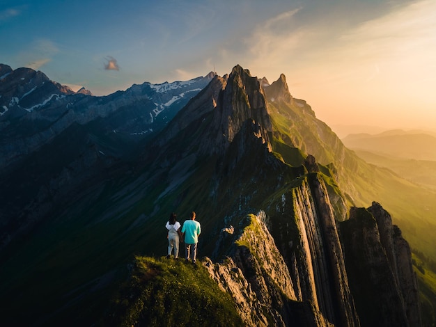 Vista trasera de hombres en la montaña contra el cielo durante la puesta de sol