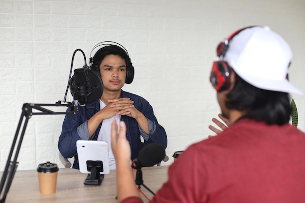 Vista trasera del invitado hablando con el anfitrión durante su programa en línea para podcast de radio