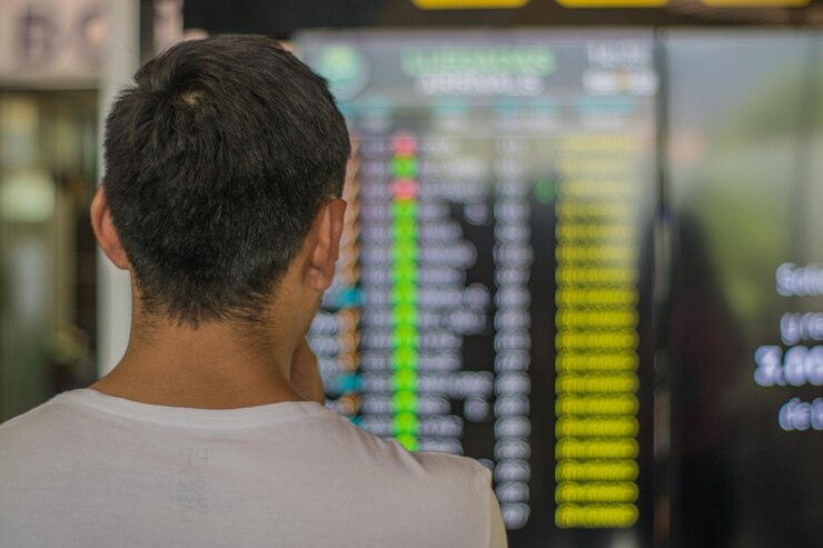 Vista trasera de un joven en el aeropuerto mirando la lista de destinos