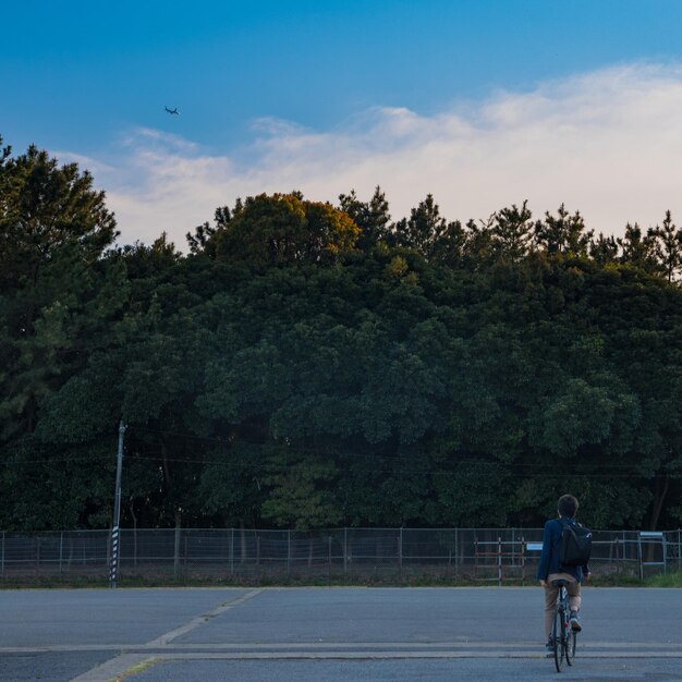 Foto vista trasera de un joven en bicicleta en el parque contra el cielo