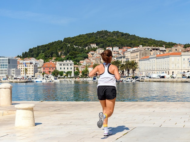 Vista trasera de una joven corredora en un trote matutino en el paseo marítimo de la ciudad costera de Split en Croacia.