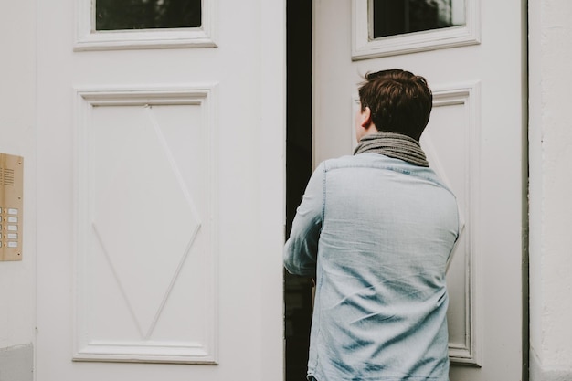 Foto vista trasera de un joven entrando en la casa