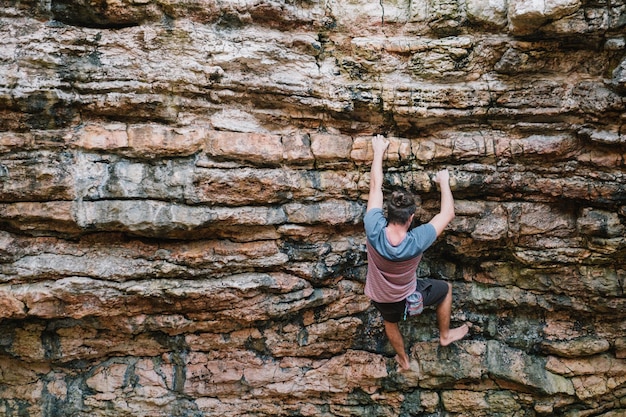 Foto vista trasera de un joven escalando la montaña