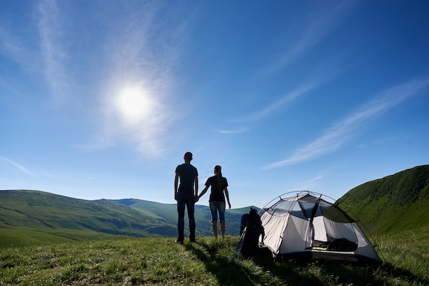 Vista trasera de una joven pareja disfrutando del descanso cerca de la carpa