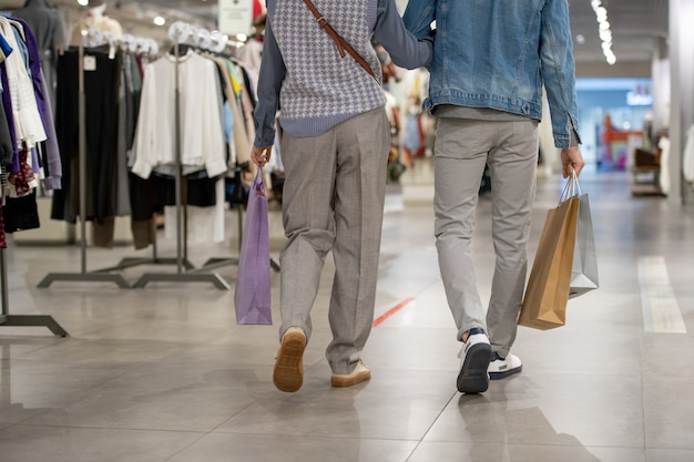 Vista trasera de la joven pareja en ropa casual caminando en una tienda de ropa