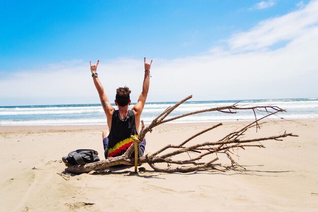 Foto vista trasera de un joven en la playa contra el cielo