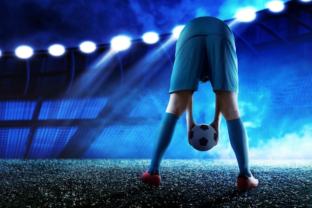 La vista trasera de un jugador de fútbol con una camiseta azul poniendo la pelota