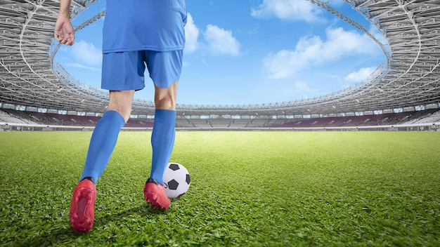 Vista trasera de un jugador de fútbol con una camiseta azul regateando el balón