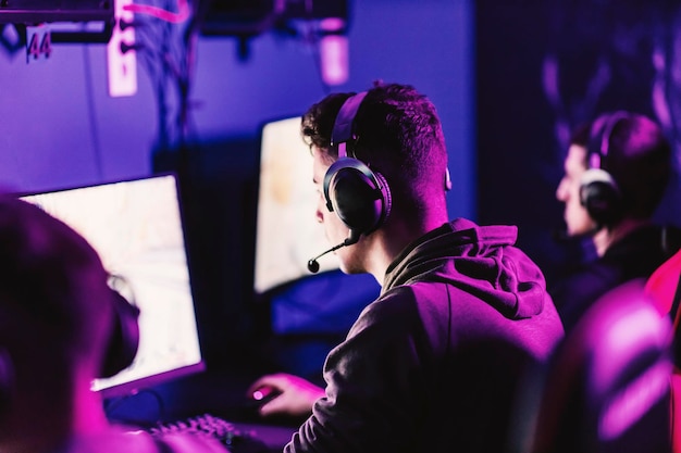 Vista trasera de un jugador profesional compitiendo en esport en una sala de juegos oscura