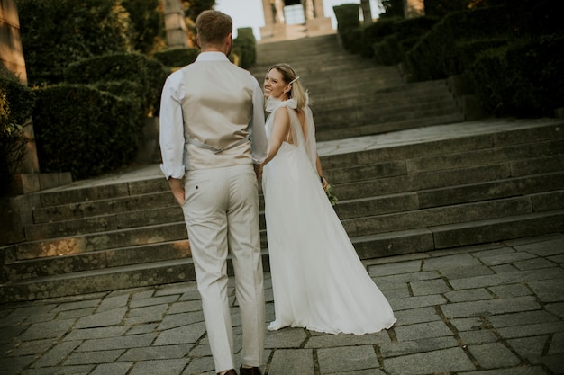 Vista trasera de la linda joven pareja de recién casados caminando por las escaleras en el parque