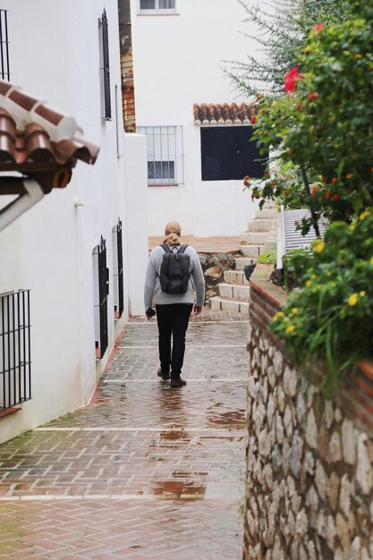 Foto vista trasera de longitud completa de un hombre caminando por un sendero en medio de edificios