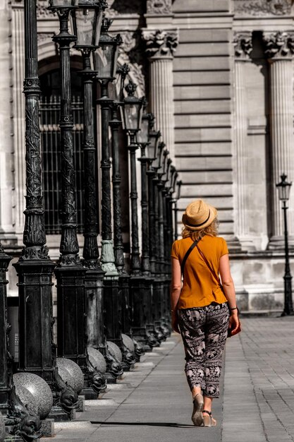 Foto vista trasera de longitud completa de una mujer caminando contra un edificio histórico