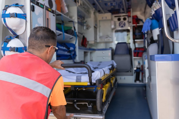 Foto vista trasera de un miembro masculino del personal médico sacando una camilla de una ambulancia