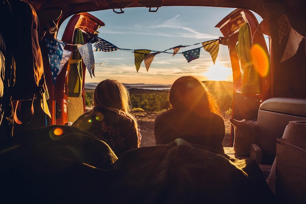 Vista trasera de una mujer acostada en un remolque de viaje durante la puesta de sol