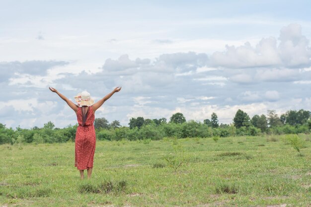 Foto vista trasera de una mujer adulta de pie en un campo de hierba contra un cielo nublado