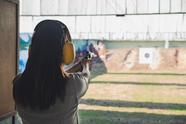 Foto vista trasera de una mujer apuntando con un arma al campo de tiro