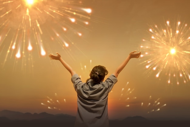 Vista trasera de una mujer asiática con una expresión feliz celebrando el año nuevo con fuegos artificiales en el cielo. Feliz año nuevo 2021